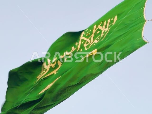 العلم الوطني للمملكة العربية السعودية، خلفية خضراء عليها كتابة عربية وسيف أبيض عليه كتابة للعقيدة الإسلامية، أو