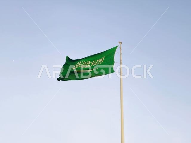 The national flag of Saudi Arabia kingdom, a green background with Arabic inscription and a sword in white, with inscription of the Islamic creed, or