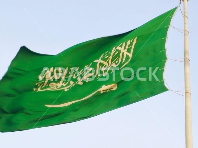 The national flag of Saudi Arabia kingdom, a green background with Arabic inscription and a sword in white, with inscription of the Islamic creed, or