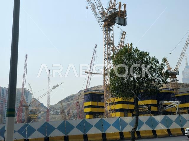 Mecca, Saudi Arabia, June 8 2024: Cranes of a construction site of a new high rise and the mountains of Makkah, Mecca  is the capital of Mecca Provinc