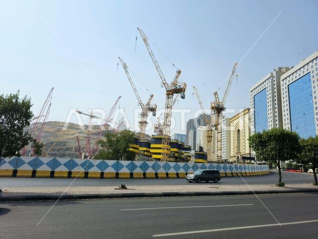 Mecca, Saudi Arabia, June 8 2024: Cranes of a construction site of a new high rise and the mountains of Makkah, Mecca  is the capital of Mecca Provinc