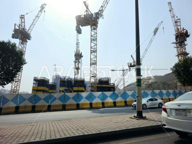 Mecca, Saudi Arabia, June 8 2024: Cranes of a construction site of a new high rise and the mountains of Makkah, Mecca  is the capital of Mecca Provinc