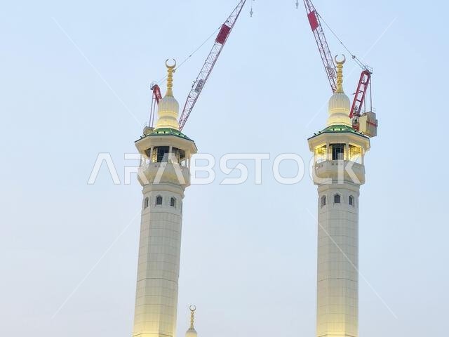 Minarets of Al Masjid Al Haram mosque around the Kaaba in Hajj, pilgrimage, Umrah, with crane towers around it for maintenance and construction purpos