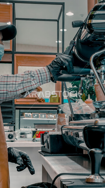 صورة مقربة ليد رجل يقوم باستخدام مكينة صنع القهوة ، ماكينة إعداد و تحضير القهوة في كافي شوب ، مشروبات ساخنة ، كافيهات و مطاعم