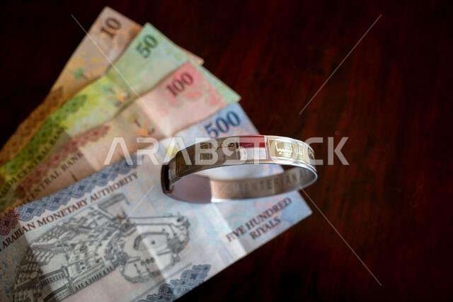 نقود، ورقة نقدية من الريال السعودي وسوار تعريف للحجاج الإندونيسيين. مفهوم الاستعداد للحج من إندونيسيا.