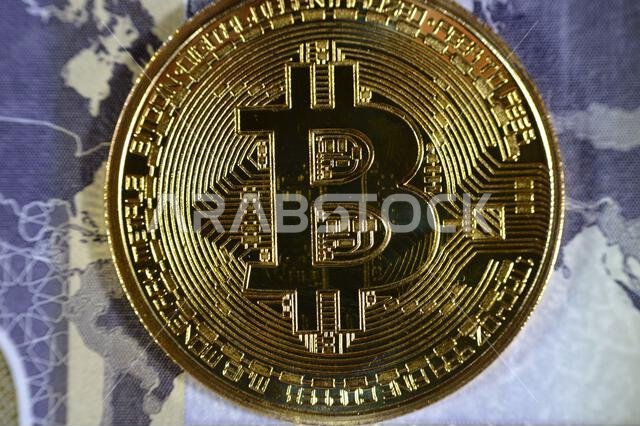 عملة الريال السعودي الورقية مزودة بعملة بيتكوين ذهبية مادية، بيتكوين هي أول عملة مشفرة لامركزية، وعقد في شبكة بيتكوين من نظير إلى نظير للتحقق من المعاملات