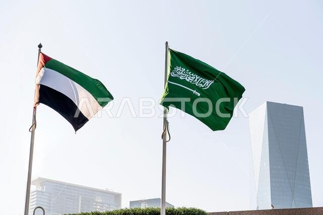 flags of Saudi Arabia and the United Arab Emirates against the background of a tall building,