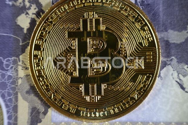 عملة الريال السعودي الورقية مزودة بعملة بيتكوين ذهبية مادية، بيتكوين هي أول عملة مشفرة لامركزية، وعقد في شبكة بيتكوين من نظير إلى نظير للتحقق من المعاملات