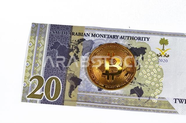 عملة الريال السعودي الورقية مزودة بعملة بيتكوين ذهبية مادية، بيتكوين هي أول عملة مشفرة لامركزية، وعقد في شبكة بيتكوين من نظير إلى نظير للتحقق من المعاملات