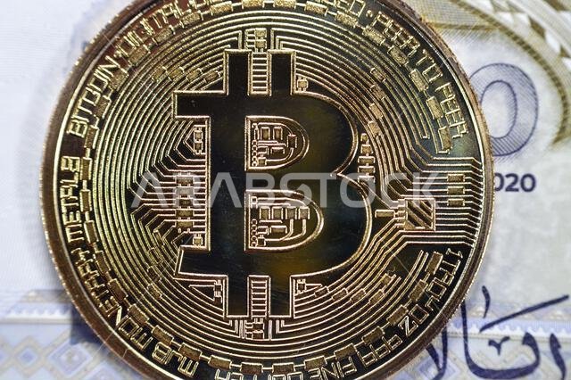 Saudi Arabia riyals banknote with Bitcoin physical golden coin, BTC the 1st decentralized cryptocurrency, nodes in P2P bitcoin network verify transact