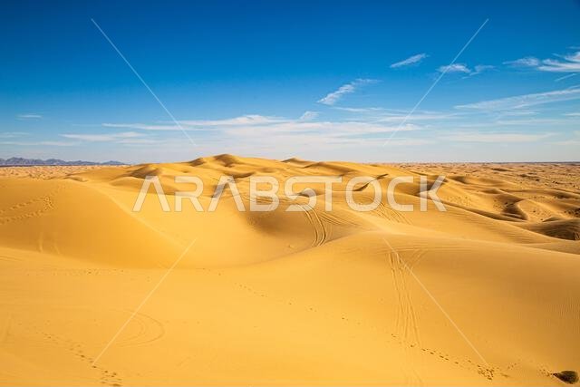 حب السفر في الصحراء: اكتشف جمال الكثبان الرملية الشاسعة الممتدة تحت سماء زرقاء صافية، مشهد مثالي للمغامرة والهدوء.