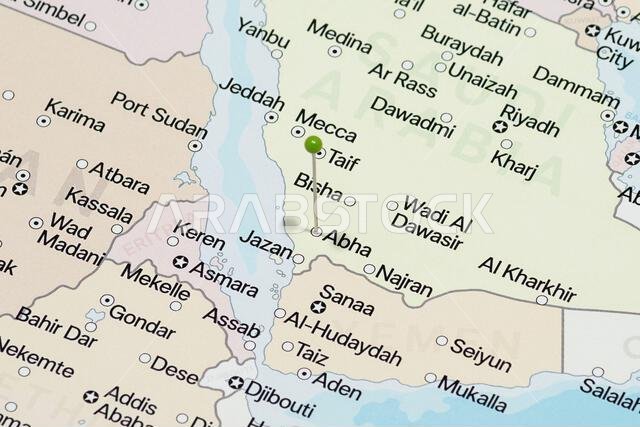 Macro photo of a green pin needle into Abha city of Saudi Arabia political map
