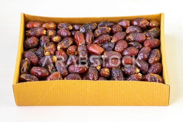 تُعرض ثمار التمر المجففة الطازجة في صندوق من الورق المقوى على خلفية بيضاء. وتُستهلك هذه الفاكهة على نطاق واسع خلال شهر رمضان المبارك. تُعرض ثمار التمر المجففة الطازجة في صندوق من الورق المقوى على خلفية بيضاء. وتُستهلك هذه الفاكهة على نطاق واسع خلال شهر رمضان المبارك.
