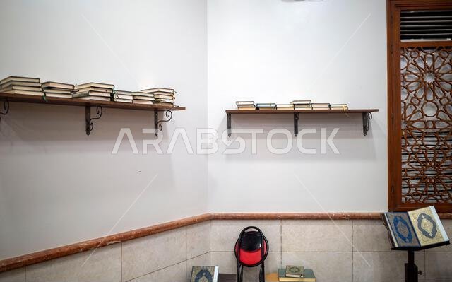The wall of a mosque in Mecca, Saudi Arabia with the Holy Quran on a wooden shelf.