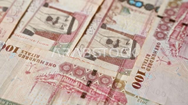 تتميز الأوراق النقدية السعودية من فئة 100 ريال بترتيبها المتقارب، مما يبرز التفاصيل والتصاميم المعقدة الموجودة على العملة.