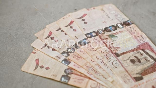 انتشرت أوراق نقدية سعودية بالريال السعودي على سطح خرساني، تُظهر تصاميم معقدة وعناصر ثقافية، مما يُبرز ثراء البلاد.
