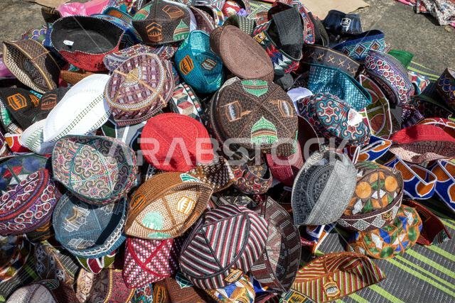 بضائع قبعات الحج الملونة لدى بائعي الهدايا التذكارية بالقرب من خيام الحجاج في منى، المملكة العربية السعودية خلال موسم الحج.