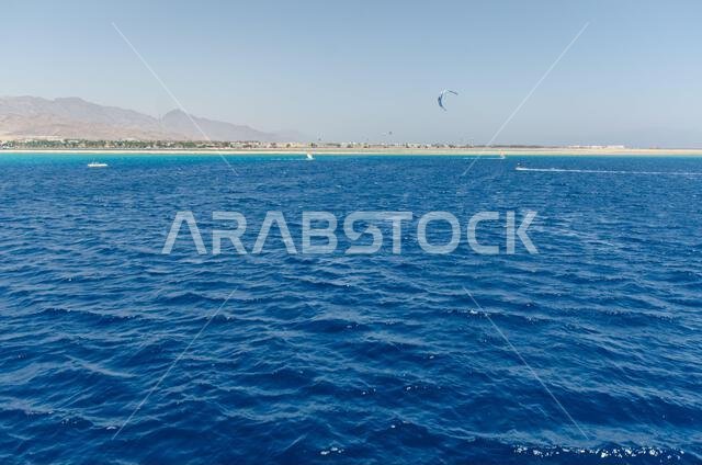 Expansive view of Red Sea with vibrant blue waves under cloudless sky. Distant mountains line horizon, creating striking contrast. Tranquil seascape e Expansive view of Red Sea with vibrant blue waves under cloudless sky. Distant mountains line horizon, creating striking contrast. Tranquil seascape e