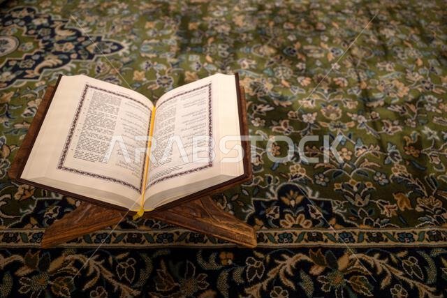 كتاب مقدس مفتوح من القرآن الكريم موضوع على سجادة خضراء في المسجد النبوي في مدينة المدينة المنورة بالمملكة العربية السعودية. كتاب مقدس مفتوح من القرآن الكريم موضوع على سجادة خضراء في المسجد النبوي في مدينة المدينة المنورة بالمملكة العربية السعودية.