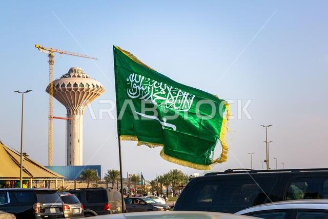 علم المملكة العربية السعودية على خلفية برج مياه الخبر. ٢٢ فبراير ٢٠٢٥. المدينة: الخبر، المملكة العربية السعودية.