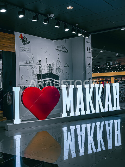 صورة لمجسم اسم مكة باللغة الانجليزية في احدى المولات التجارية ، خلفية للكعبة المشرفة ، تصميم هندسي فني جذاب ، مجمع للتسوق في مكة المكرمة في المملكة العربية السعودية