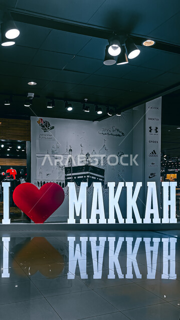 صورة لمجسم اسم مكة باللغة الانجليزية في احدى المولات التجارية ، خلفية للكعبة المشرفة ، تصميم هندسي فني جذاب ، مجمع للتسوق في مكة المكرمة في المملكة العربية السعودية