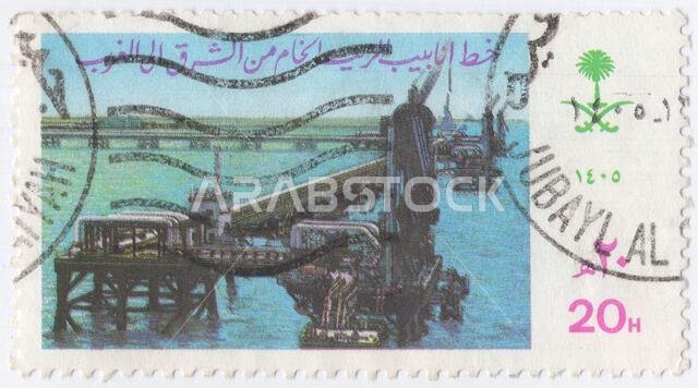SAUDI ARABIA - 1985 June 9: 20 halalas multicolored postage stamp depicting East-West Pipeline as a symbol of the Petrochemical Industry. Tanker Pier (berth) in Yanbu Commercial Port. It is one of the oldest sea ports along the Red Sea. The port is connected to the holy cities, especially the one in Medina. Moreover, it has an economic importance as it located in an economically vital area. It also receives pilgrims SAUDI ARABIA - 1985 June 9: 20 halalas multicolored postage stamp depicting East-West Pipeline as a symbol of the Petrochemical Industry. Tanker Pier (berth) in Yanbu Commercial Port. It is one of the oldest sea ports along the Red Sea. The port is connected to the holy cities, especially the one in Medina. Moreover, it has an economic importance as it located in an economically vital area. It also receives pilgrims