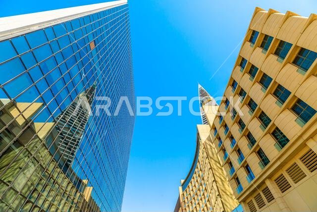 Riyadh , Saudi Arabia - Jannuary 8, 2025: Low angle view of modern buildings in Riyadh with blue sky, featuring Al Faisaliah Tower reflecting on a