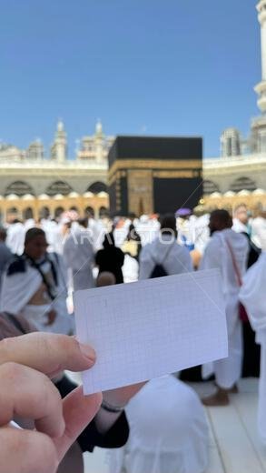 A pilgrim holds a small notebook with a heart doodle in front of the Kaaba in Mecca, Saudi Arabia. The sacred site is surrounded by worshippers