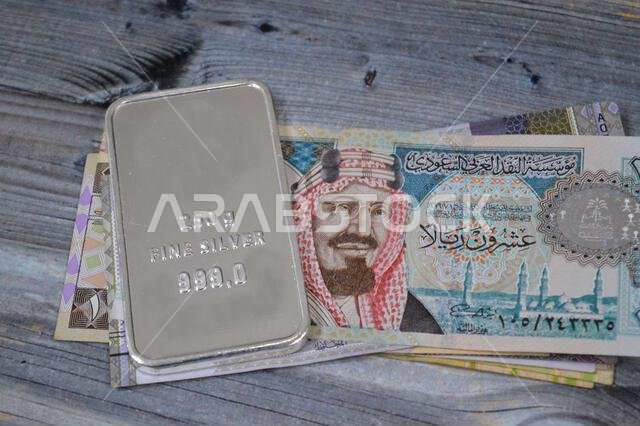 أوراق نقدية سعودية من فئة الريال، وسبائك فضية ثمينة وزنها 250 غرام من الفضة الخالصة. يتأثر سعر الفضة بالمضاربة والعرض والطلب.