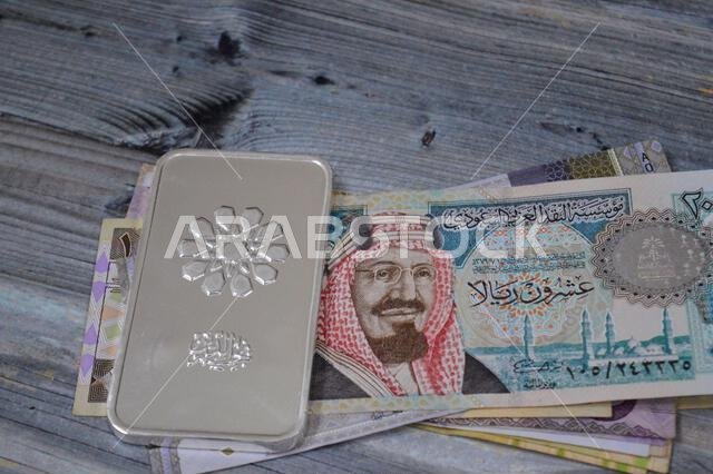 القاهرة، مصر، 20 فبراير 2025: أوراق نقدية من الريال السعودي وسبائك فضة نقية من تصميم نجم الدين بوزن 250 غرامًا، استثمار في الفضة، سعر الصرف، i القاهرة، مصر، 20 فبراير 2025: أوراق نقدية من الريال السعودي وسبائك فضة نقية من تصميم نجم الدين بوزن 250 غرامًا، استثمار في الفضة، سعر الصرف، i