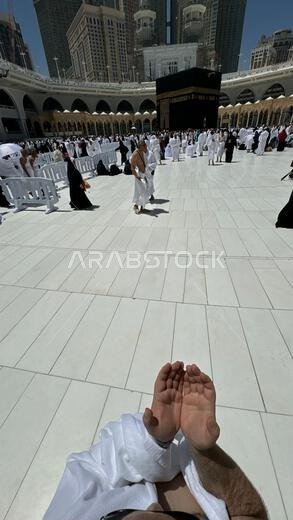 A bald man poses for a photo in front of the Kaaba at noon after performing Umrah at Masjid al-Haram, Mecca. A sacred Islamic pilgrimage in the heart