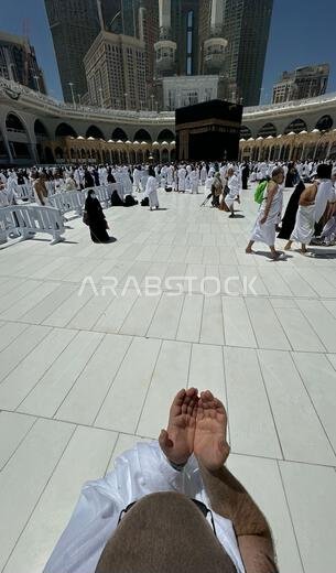 رجل أصلع يقف لالتقاط صورة أمام الكعبة المشرفة ظهرًا بعد أداء العمرة في المسجد الحرام بمكة المكرمة، وهي مناسك الحج الإسلامية المقدسة في قلب العالم.