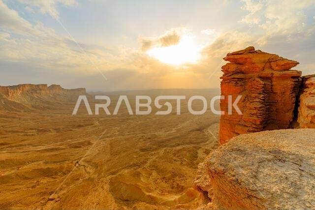 غروب الشمس على التكوينات الصخرية الواقعة على حافة العالم في جبل الفهرين بالقرب من الرياض، المملكة العربية السعودية، يخلق منظراً خلاباً لغروب الشمس فوق الصحراء الشاسعة