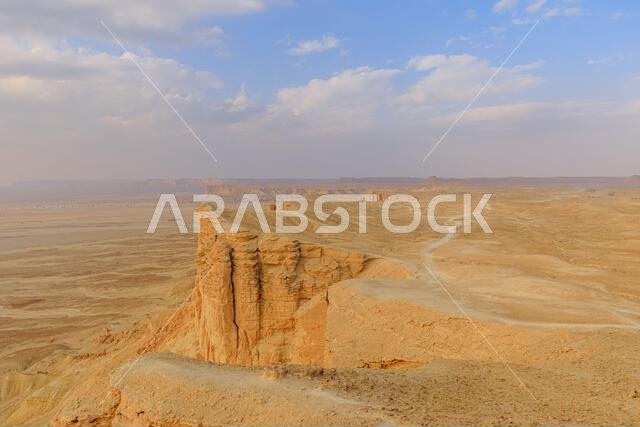 Panoramic view of the stunning Jebel fihrayn, or edge of the world, revealing dramatic cliffs and a vast desert landscape beneath a cloudy sky in Panoramic view of the stunning Jebel fihrayn, or edge of the world, revealing dramatic cliffs and a vast desert landscape beneath a cloudy sky in
