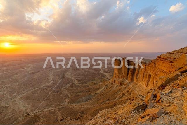 غروب شمس خلاب فوق المناظر الطبيعية الصحراوية الشاسعة، كما يُرى من منحدرات سلسلة جبال طويق في الرياض، المملكة العربية السعودية، يُبرز جمالها وروعتها. غروب شمس خلاب فوق المناظر الطبيعية الصحراوية الشاسعة، كما يُرى من منحدرات سلسلة جبال طويق في الرياض، المملكة العربية السعودية، يُبرز جمالها وروعتها.