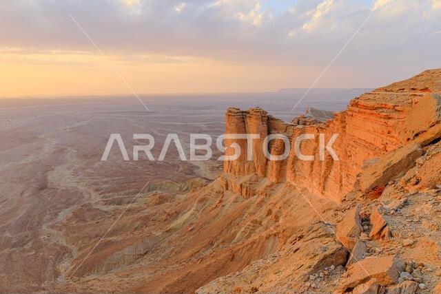 تُضيء الساعة الذهبية حافة جرف العالم عند غروب الشمس، مُظهرةً منحدرات سلسلة جبال طويق في الرياض، المملكة العربية السعودية.