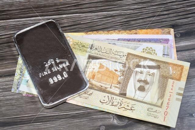أوراق نقدية سعودية من فئة الريال، وسبائك فضية ثمينة وزنها 250 غرام من الفضة الخالصة. يتأثر سعر الفضة بالمضاربة والعرض والطلب. أوراق نقدية سعودية من فئة الريال، وسبائك فضية ثمينة وزنها 250 غرام من الفضة الخالصة. يتأثر سعر الفضة بالمضاربة والعرض والطلب.