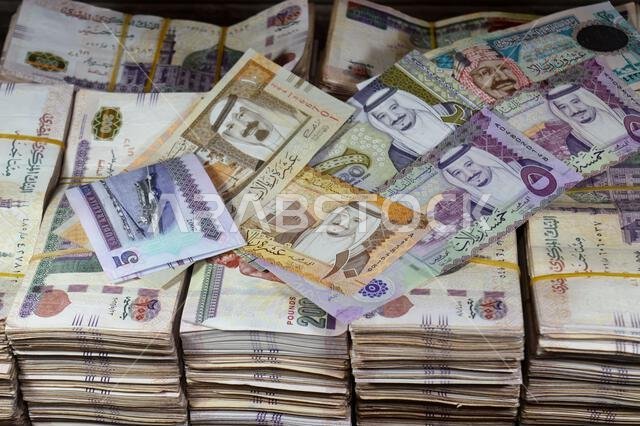 Saudi Arabia riyals SAR cash money bills banknotes and Piles of Egypt money thousands of Pounds currency banknotes bills of 200 EGP LE, Egyptian money