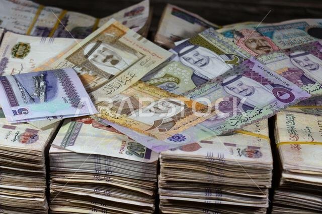 Saudi Arabia riyals SAR cash money bills banknotes and Piles of Egypt money thousands of Pounds currency banknotes bills of 200 EGP LE, Egyptian money