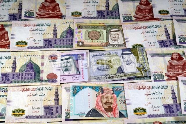 Saudi Arabia riyals SAR cash money bills banknotes and Piles of Egypt money thousands of Pounds currency banknotes bills of 200 EGP LE, Egyptian money
