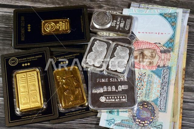 Cairo, Egypt, May 2 2025: Riyals money banknote and BTC Bullion Trading Center pure gold bars and fine silver bars of different weights, gold investme