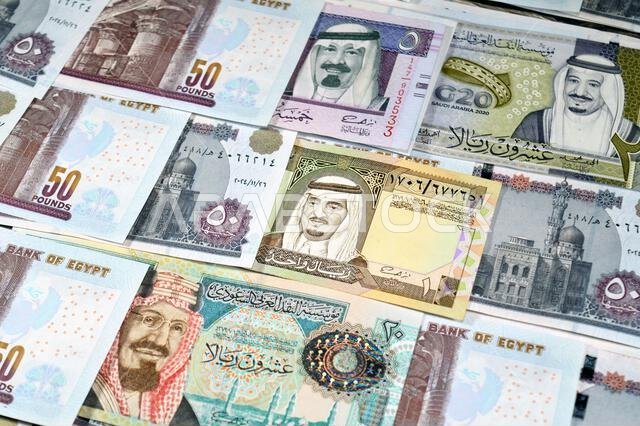 Saudi Arabia riyals SAR cash money bills banknotes and Pile of Egypt money hundreds of Pounds currency banknotes bills of 50 EGP LE, Egyptian money ex