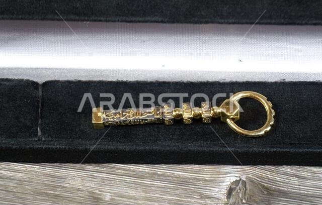 Translation of Arabic of Quran verse (Indeed, we have granted you a clear victory) and Allah word on a golden Kaaba Ka'bah key model, gold model of Ka Translation of Arabic of Quran verse (Indeed, we have granted you a clear victory) and Allah word on a golden Kaaba Ka'bah key model, gold model of Ka