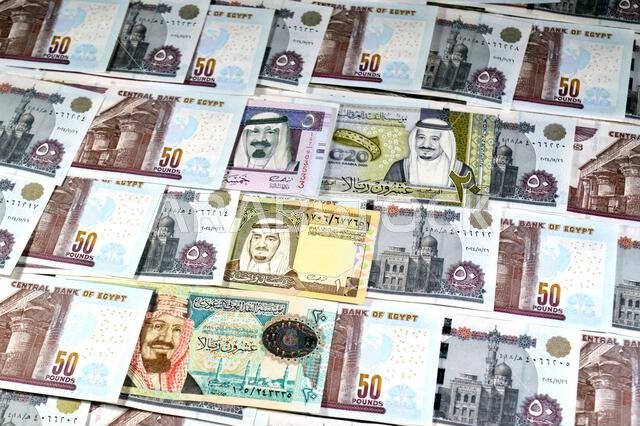 Saudi Arabia riyals SAR cash money bills banknotes and Pile of Egypt money hundreds of Pounds currency banknotes bills of 50 EGP LE, Egyptian money ex