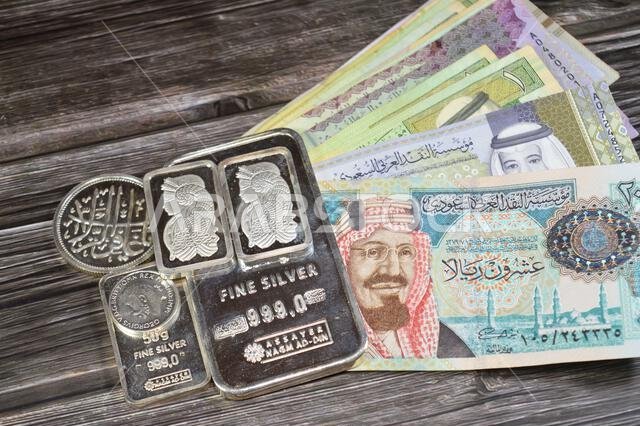 القاهرة، مصر، 16 مايو 2025: أوراق نقدية من الريال السعودي وسبائك نجم الدين الفضية الخالصة، الاستثمار في الفضة، سعر الصرف، التضخم القاهرة، مصر، 16 مايو 2025: أوراق نقدية من الريال السعودي وسبائك نجم الدين الفضية الخالصة، الاستثمار في الفضة، سعر الصرف، التضخم