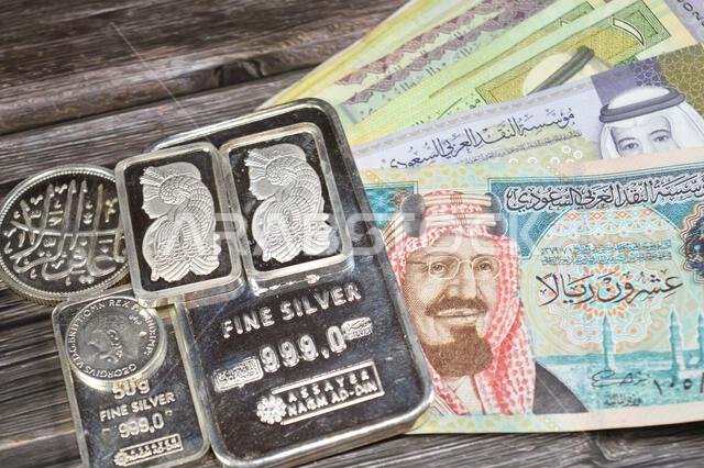 Cairo, Egypt, May 16 2025: Saudi Arabia riyals money banknotes and Nagm Ad-Din pure fine silver bars, silver investment, exchange price rate, inflatio