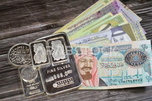 القاهرة، مصر، 16 مايو 2025: أوراق نقدية من الريال السعودي وسبائك نجم الدين الفضية الخالصة، الاستثمار في الفضة، سعر الصرف، التضخم