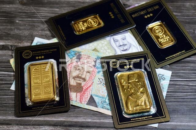 Cairo, Egypt, May 2 2025: Saudi Arabian riyals money and 24K karat BTC Bullion Trading Center pure yellow gold bars, gold investment, exchange price r