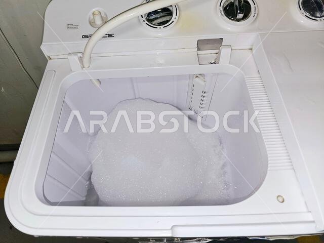 Mecca, Saudi Arabia, June 22 2024: manual top load washing machine, laundry clothes washer, a home appliance used to wash laundry, user adds laundry d Mecca, Saudi Arabia, June 22 2024: manual top load washing machine, laundry clothes washer, a home appliance used to wash laundry, user adds laundry d